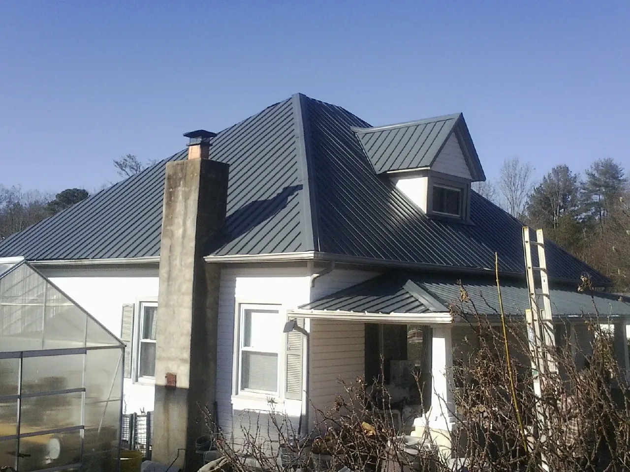 Dark blue standing seam metal roof on a white farmhouse with dormer — Slate & Tile Roof Repair by Roofing Brothers in Pine Beach