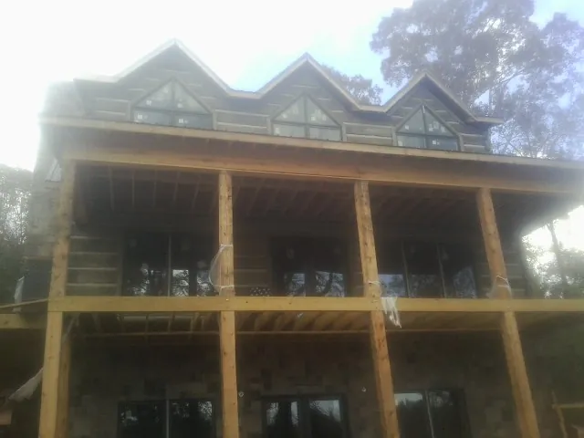 Dormers and porch framing on a large log home under construction — Roof Coating work by our crew in Pine Beach