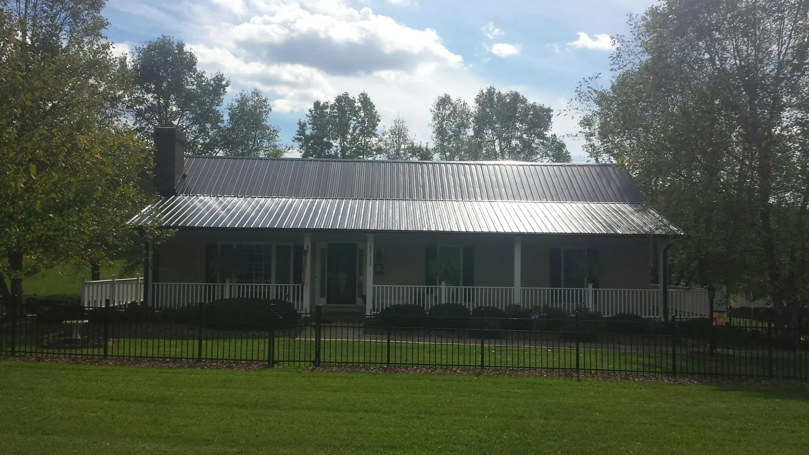Gray metal roof on a brick ranch with a full width front porch — Gutter Guard Installation work by our crew in Pine Beach