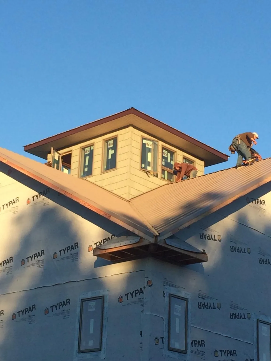 Roofers working around a rooftop cupola on a new metal roof at sunset — Roof Waterproofing in Pine Beach by Roofing Brothers
